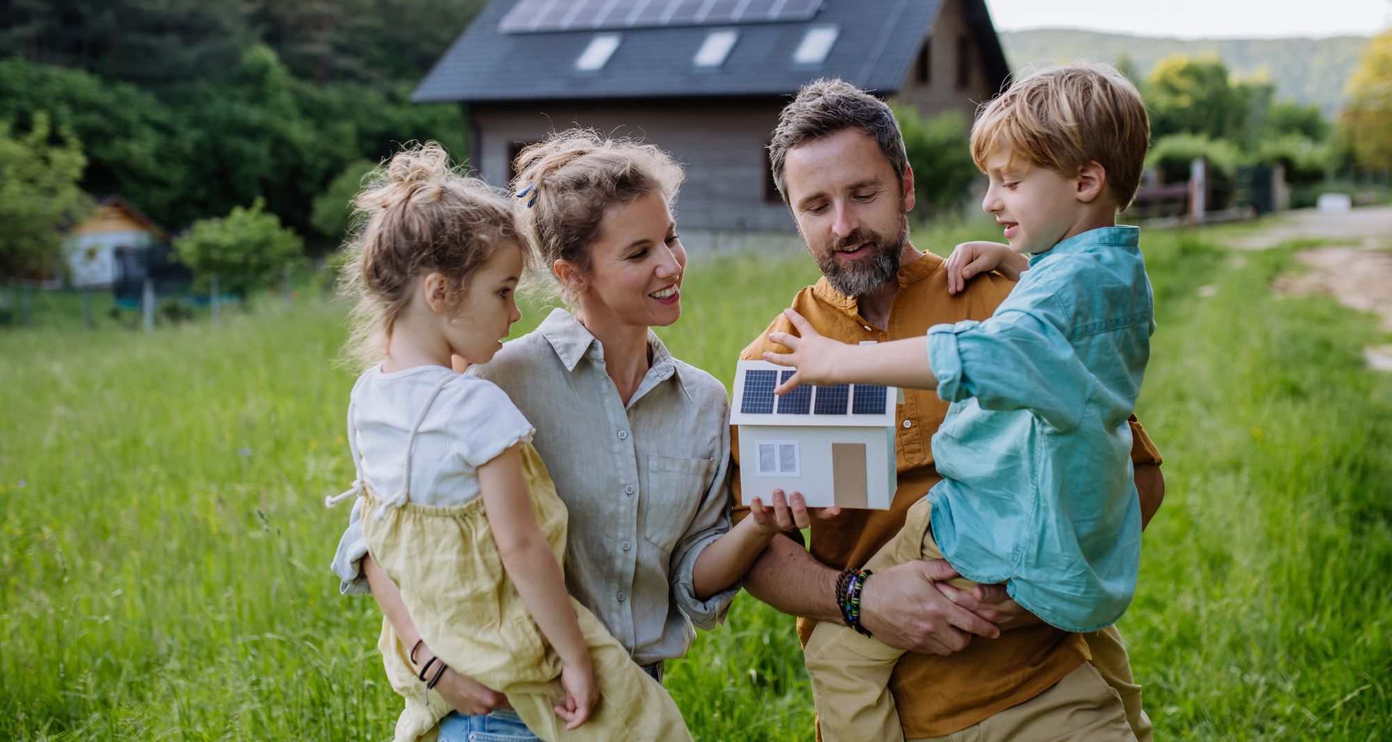 avantages panneaux solaires - Famille tenant une maquette d'une maison avec des panneaux solaires