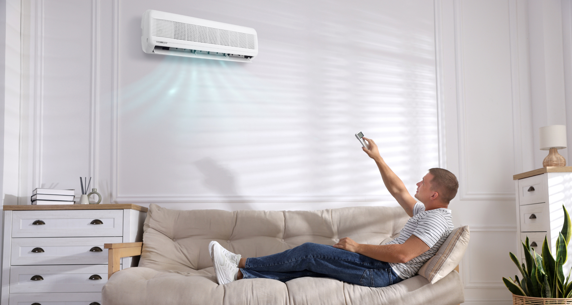 Homme sur son canapé qui active la climatisation